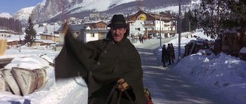 Movie still from “The Pink Panther” (1963), directed by Blake Edwards – A man wearing a hat and a coat on the side of a road; Medium shot, Low angle