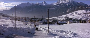 Movie still from “The Pink Panther” (1963), directed by Blake Edwards – A car driving down a road in the middle of a snow covered town; Extreme Wide shot, High angle