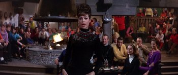 Movie still from “The Pink Panther” (1963), directed by Blake Edwards – A woman standing in front of a group of people; Medium shot, Over the shoulder angle