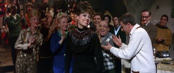 Movie still from “The Pink Panther” (1963), directed by Blake Edwards – A group of people standing around a woman; Medium shot, Over the shoulder angle