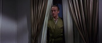 Movie still from “The Pink Panther” (1963), directed by Blake Edwards – A man in a green suit standing in front of a curtain; Medium shot, Low angle