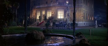 Movie still from “The Pink Panther” (1963), directed by Blake Edwards – A fountain in front of a large building at night; Extreme Wide shot, High angle