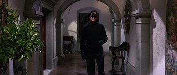 Movie still from “The Pink Panther” (1963), directed by Blake Edwards – A man wearing a black mask and black gloves standing in a hallway; Medium shot, Low angle