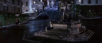 Movie still from “The Pink Panther” (1963), directed by Blake Edwards – A street scene with a fountain in the middle of the night; Extreme Wide shot, High angle