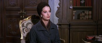 Movie still from “The Pink Panther” (1963), directed by Blake Edwards – A woman in a gray coat and a brown hat; Close Up shot, Over the shoulder angle