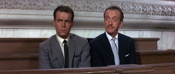 Movie still from “The Pink Panther” (1963), directed by Blake Edwards – Two men in suits and ties sitting in a courtroom; Close Up shot, Low angle