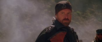 Movie still from “The Postman” (1997), directed by Kevin Costner – A man with a beard wearing a hat and a jacket; Close Up shot, Over the shoulder angle