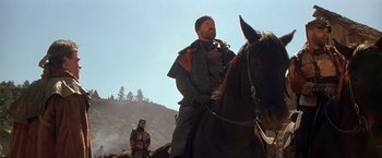 Movie still from “The Postman” (1997), directed by Kevin Costner – A man riding on the back of a brown horse; Medium shot, Low angle