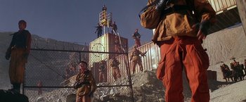 Movie still from “The Postman” (1997), directed by Kevin Costner – A group of men standing on top of a metal fence; Wide shot, Low angle