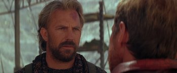 Movie still from “The Postman” (1997), directed by Kevin Costner – A man with a bandage on his head is talking to another man; Close Up shot, Over the shoulder angle
