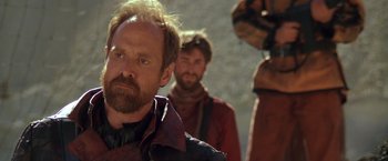 Movie still from “The Postman” (1997), directed by Kevin Costner – A man with a goatee and a beard; Close Up shot, Over the shoulder angle