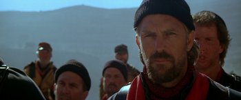 Movie still from “The Postman” (1997), directed by Kevin Costner – A group of men standing next to each other on top of a hill; Close Up shot, Over the shoulder angle