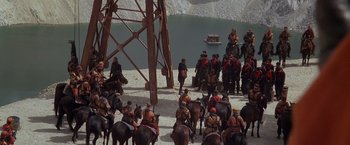 Movie still from “The Postman” (1997), directed by Kevin Costner – A group of people riding horses next to a body of water; Extreme Wide shot, High angle