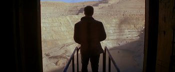 Movie still from “The Postman” (1997), directed by Kevin Costner – A man standing on a railing looking out at a mountain; Extreme Wide shot, High angle