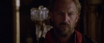 Movie still from “The Postman” (1997), directed by Kevin Costner – A person with a beard looking at the camera; Close Up shot, Low angle
