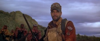 Movie still from “The Postman” (1997), directed by Kevin Costner – A man with a hat and a rifle in his hands; Close Up shot, Low angle