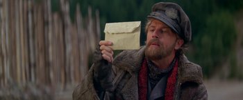 Movie still from “The Postman” (1997), directed by Kevin Costner – A man holding an envelope in front of his face; Close Up shot, Low angle