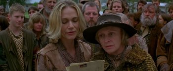 Movie still from “The Postman” (1997), directed by Kevin Costner – Two women are looking at a piece of paper in front of a group of people; Close Up shot, High angle