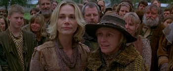 Movie still from “The Postman” (1997), directed by Kevin Costner – Two women are standing next to each other in front of a group of people; Close Up shot, Over the shoulder angle