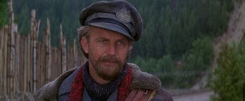 Movie still from “The Postman” (1997), directed by Kevin Costner – A person with a beard wearing a hat; Close Up shot, Over the shoulder angle