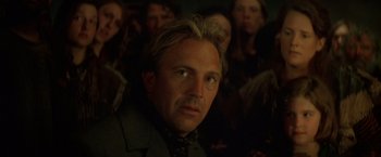 Movie still from “The Postman” (1997), directed by Kevin Costner – A person wearing a suit and tie; Close Up shot, Low angle