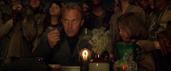 Movie still from “The Postman” (1997), directed by Kevin Costner – A group of people sitting around a dinner table; Close Up shot, Over the shoulder angle