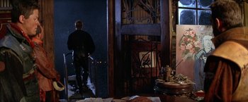 Movie still from “The Postman” (1997), directed by Kevin Costner – A man standing in front of an open door; Wide shot, Low angle