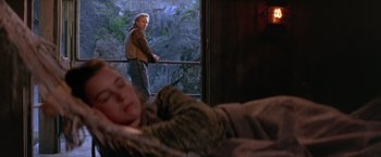 Movie still from “The Postman” (1997), directed by Kevin Costner – A man and a sleeping woman in a room; Wide shot, Over the shoulder angle