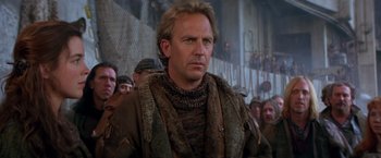 Movie still from “The Postman” (1997), directed by Kevin Costner – A person in a crowd wearing a sweater; Close Up shot, Low angle