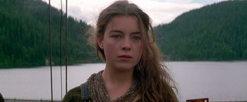 Movie still from “The Postman” (1997), directed by Kevin Costner – A woman with long brown hair standing in front of a body of water; Close Up shot, Over the shoulder angle