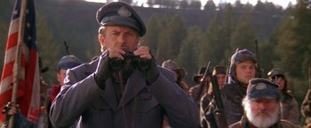 Movie still from “The Postman” (1997), directed by Kevin Costner – A man in a military uniform looking through binoculars; Close Up shot, Over the shoulder angle