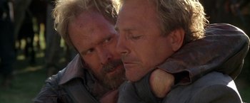 Movie still from “The Postman” (1997), directed by Kevin Costner – A man with a beard is looking at another man with a beard; Close Up shot, Over the shoulder angle