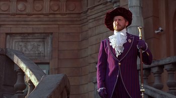 Movie still from “The Princess Diaries 2: Royal Engagement” (2004), directed by Garry Marshall – A man in a purple suit and a red hat; Medium shot, Low angle