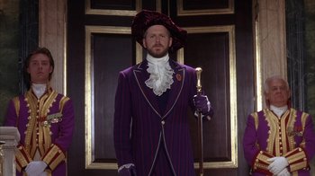 Movie still from “The Princess Diaries 2: Royal Engagement” (2004), directed by Garry Marshall – A man in a purple suit with a purple hat; Medium shot, Low angle