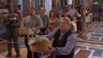 Movie still from “The Princess Diaries 2: Royal Engagement” (2004), directed by Garry Marshall – A group of people standing in a room holding a basket; Medium shot, High angle