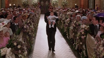 Movie still from “The Princess Diaries 2: Royal Engagement” (2004), directed by Garry Marshall – A man holding a baby while walking down the aisle; Wide shot, High angle