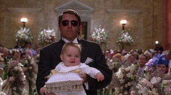 Movie still from “The Princess Diaries 2: Royal Engagement” (2004), directed by Garry Marshall – A man holding a baby in his arms in front of a crowd; Medium shot, Low angle
