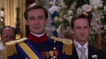 Movie still from “The Princess Diaries 2: Royal Engagement” (2004), directed by Garry Marshall – A man in a military uniform stands next to another man in a suit and tie; Close Up shot, Low angle