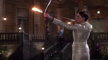 Movie still from “The Princess Diaries 2: Royal Engagement” (2004), directed by Garry Marshall – A woman in a white dress holding a bow and arrow; Medium shot, Over the shoulder angle