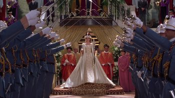Movie still from “The Princess Diaries 2: Royal Engagement” (2004), directed by Garry Marshall – A woman in a white dress standing in front of a group of men; Wide shot, Low angle