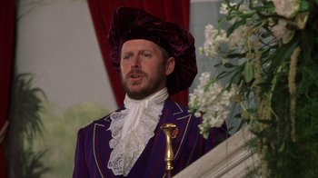 Movie still from “The Princess Diaries 2: Royal Engagement” (2004), directed by Garry Marshall – A man wearing a purple suit and a purple hat; Close Up shot, Over the shoulder angle