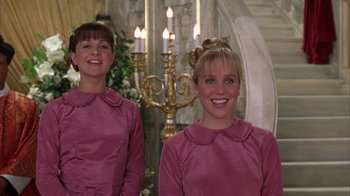 Movie still from “The Princess Diaries 2: Royal Engagement” (2004), directed by Garry Marshall – A couple of women standing next to each other in front of candles; Medium shot, Low angle