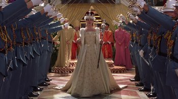 Movie still from “The Princess Diaries 2: Royal Engagement” (2004), directed by Garry Marshall – A woman in a long dress standing in front of a group of men; Wide shot, Over the shoulder angle