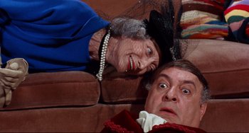 Movie still from “The Producers” (1967), directed by Mel Brooks – An old woman and a man are sitting on a couch; Medium shot, High angle