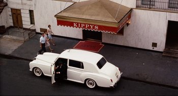 Movie still from “The Producers” (1967), directed by Mel Brooks – A white car parked on the side of the street; Wide shot, High angle