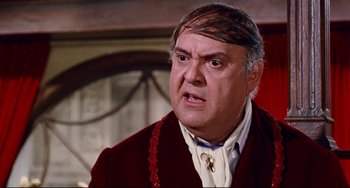 Movie still from “The Producers” (1967), directed by Mel Brooks – An older man in a red jacket and white shirt; Close Up shot, Over the shoulder angle