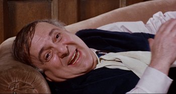 Movie still from “The Producers” (1967), directed by Mel Brooks – An older man laying on a bed smiling for the camera; Close Up shot, High angle