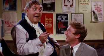 Movie still from “The Producers” (1967), directed by Mel Brooks – Two men in suits are talking and laughing; Medium shot, Over the shoulder angle
