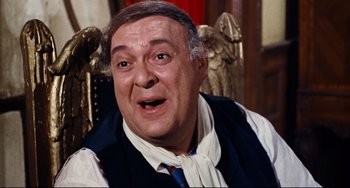 Movie still from “The Producers” (1967), directed by Mel Brooks – An older man sitting in a chair wearing a vest and a tie; Close Up shot, High angle