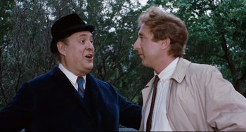 Movie still from “The Producers” (1967), directed by Mel Brooks – Two men in suits and hats talking to each other outside; Close Up shot, Over the shoulder angle